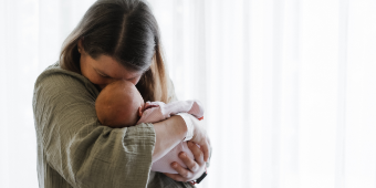 Frisch gebackene Mama kuschelt verliebt mit ihrem Baby auf der Wochenbettstation – Stirn an Stirn.