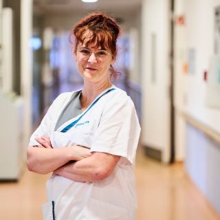 Pflegefachkraft Das Bild zeigt eine Pflegefachkraft in einem Stationsflur stehen.