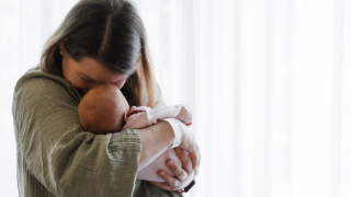 Frisch gebackene Mama kuschelt verliebt mit ihrem Baby auf der Wochenbettstation – Stirn an Stirn.