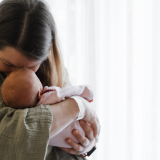 Frisch gebackene Mama kuschelt verliebt mit ihrem Baby auf der Wochenbettstation – Stirn an Stirn.