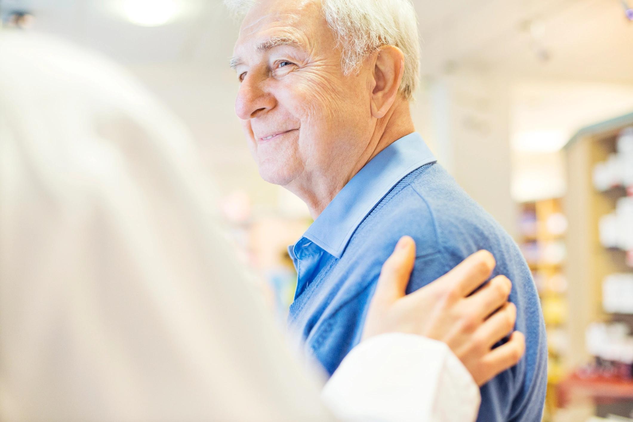 Das Bild zeigt einen Arzt der einem älteren Patienten eine Hand auf den Arm legt.