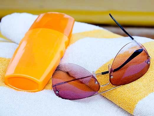 Bild: Sonnencreme, Handtuch und Sonnenbrille